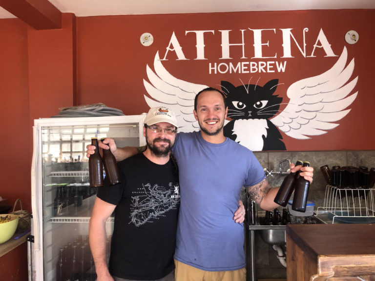 Roger and Seth standing withe beer bottles in front of Athena Homebrew bar.