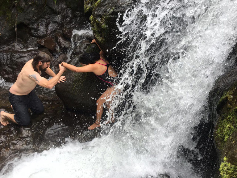 Roger reaching for Malena under a water fall.